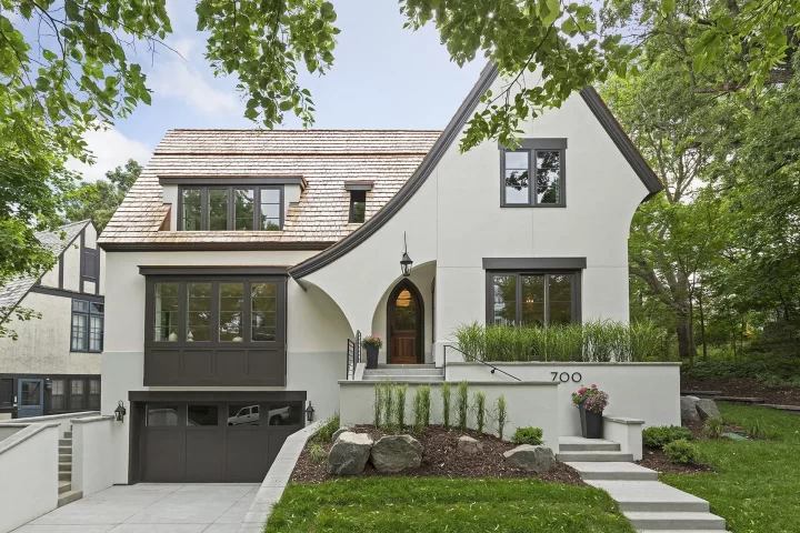 Modern Tudor style custom home in St Paul's Crocus Hill neighborhood with arched entry, dark window framing, and integrated garage on a landscaped urban lot.