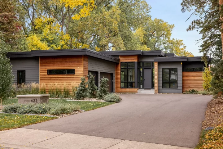 Contemporary custom home in Golden Valley featuring flat rooflines, natural wood siding, dark accents, and expansive windows, built by Detail Homes.