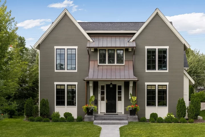 Modern Colonial style home in St Paul with vertical siding, black framed windows, and metal roof accents.