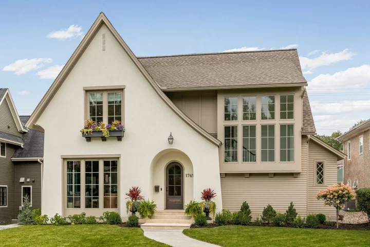 Custom Tudor style home with steep gable roof, arched entry, and white exterior in the Highland neighborhood of St Paul, Built by Detail Homes.