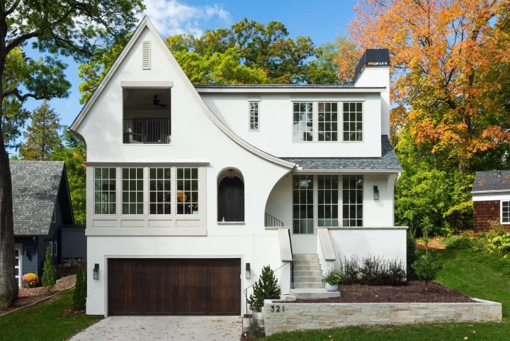 Modern Tudor style custom home in Wayzata with white exterior, arched front entry and steep roofline. Built by Detail Homes
